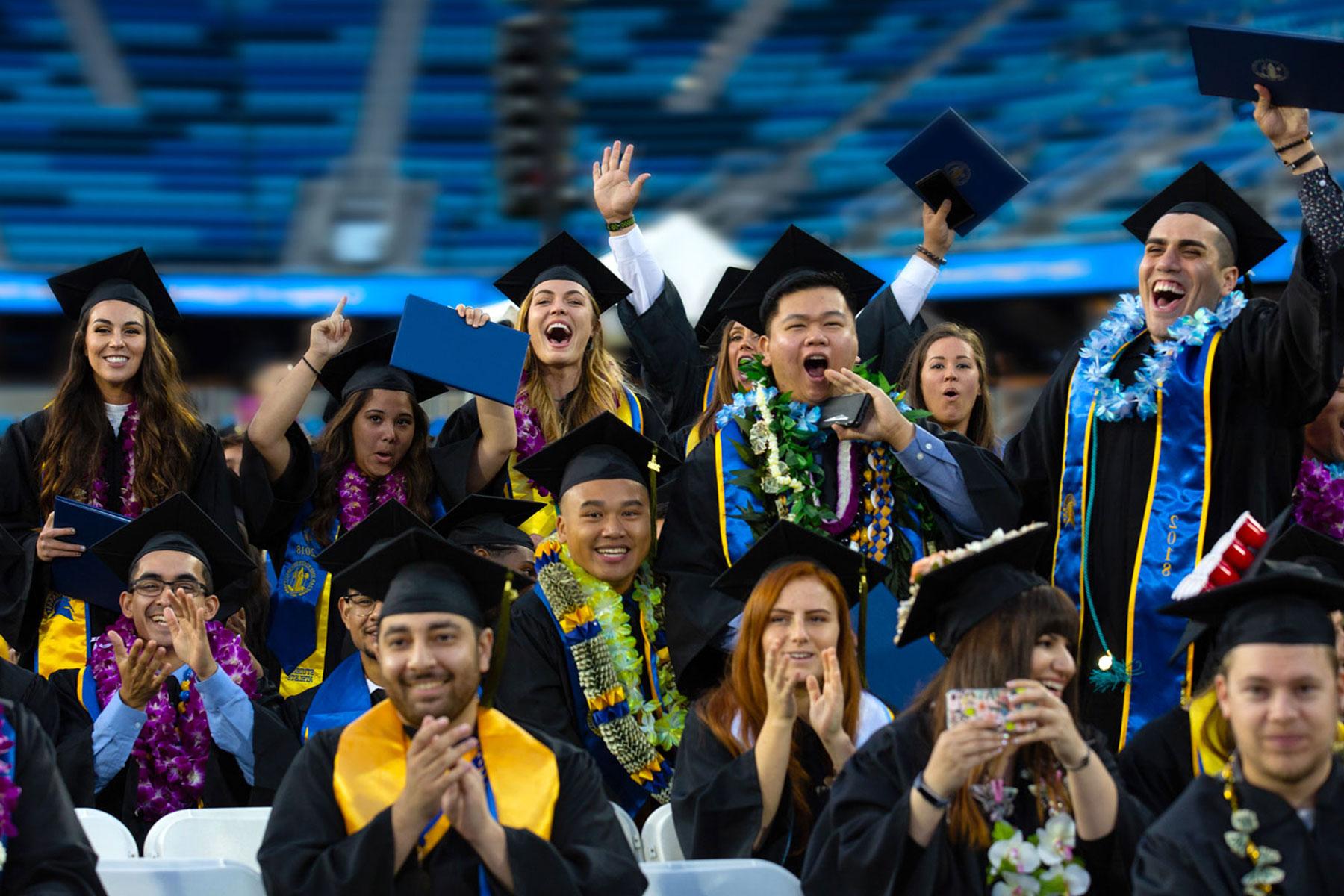 Students dressed in regalia happy during graduation ceremony.