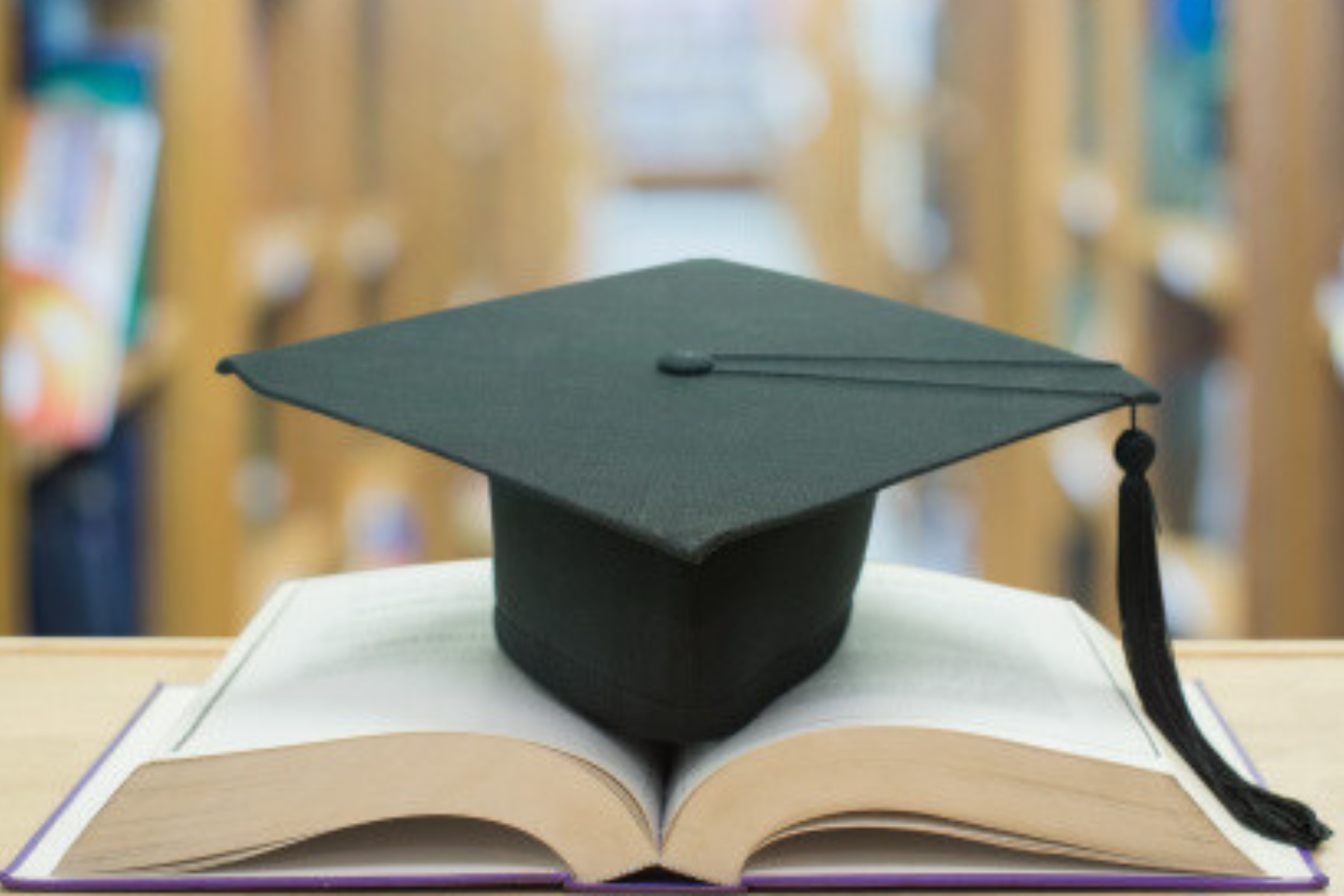 Graduate cap placed atop an open textbook